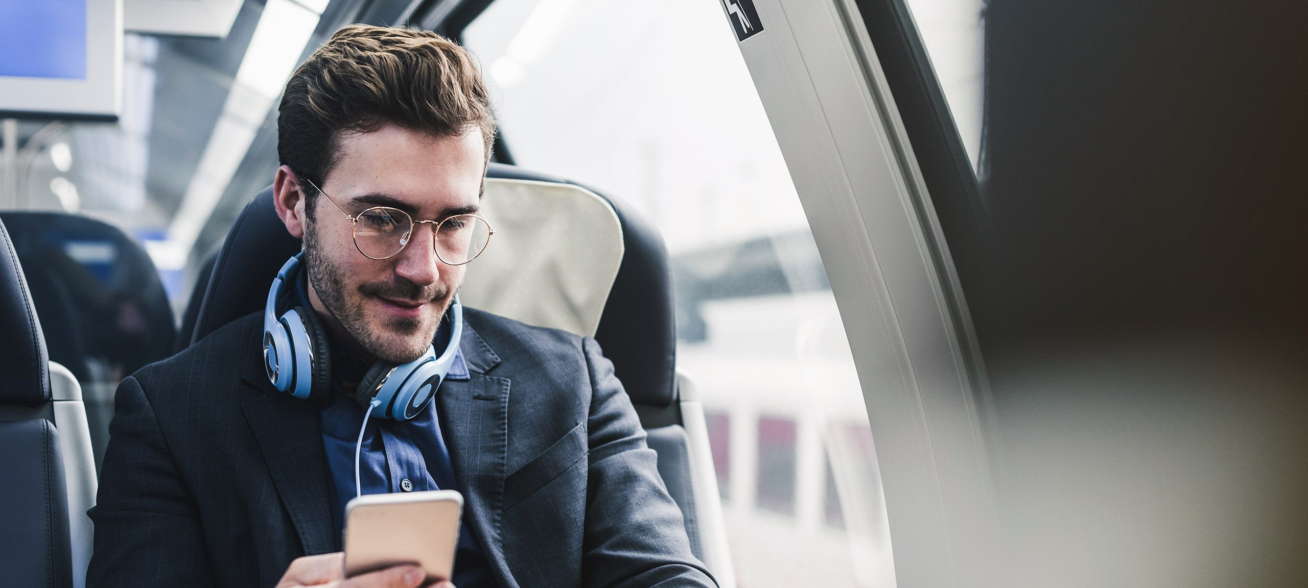 Ein Mann sitzt im Zug und schaut auf sein Handy